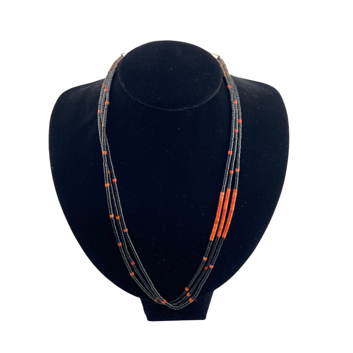 A multi-strand beaded necklace with black and orange beads, displayed on a black velvet jewelry bust against a white background.